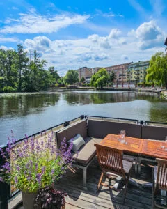 Flytande uteservering vid Stångs magasin med sittgrupp i trä och lavendel, med utsikt över Stångån i centrala Linköping