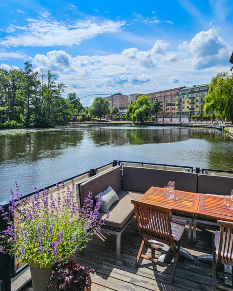 Flytande uteservering vid Stångs magasin med sittgrupp i trä och lavendel, med utsikt över Stångån i centrala Linköping