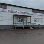Entrén till Motala Återvinning, en ljus industribyggnad med ramp och skylt ovanför dörren, på en mulen dag