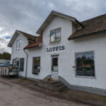 Vitputsad byggnad med skylt "LOPPIS" på fasaden, tegeltak och stentrappa vid entrén, i Motala kommun en mulen höstdag