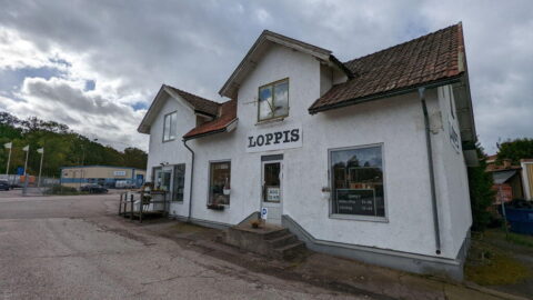 Vitputsad byggnad med skylt "LOPPIS" på fasaden, tegeltak och stentrappa vid entrén, i Motala kommun en mulen höstdag