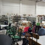 Stor secondhandbutik i Linköping fylld med stolar, bord, porslin och köksutrustning på hyllor längs väggarna.