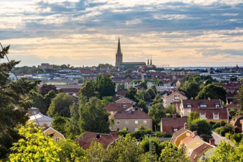 Utsikt från Koberget över Linköpings villakvarter och stadssiluett med Linköpings domkyrkas höga torn mot en dramatisk himmel