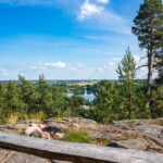 Utsikt från Juteberget i Borensberg över sjö, tallskog och Östgötaslätten mot Brunneby en sommardag med blå himmel