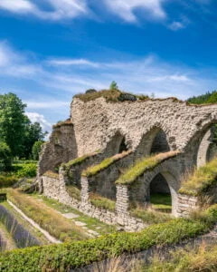 Alvastra klosterruin med välbevarade stenbågar och valv omgivna av grönska under blå himmel, Ödeshögs kommun i Östergötland