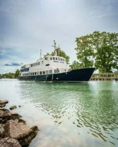 Passagerarfartyget Wasa Lejon förtöjt vid Bergs slussar längs Göta kanal, omgivet av gröna lövträd och stilla vatten.