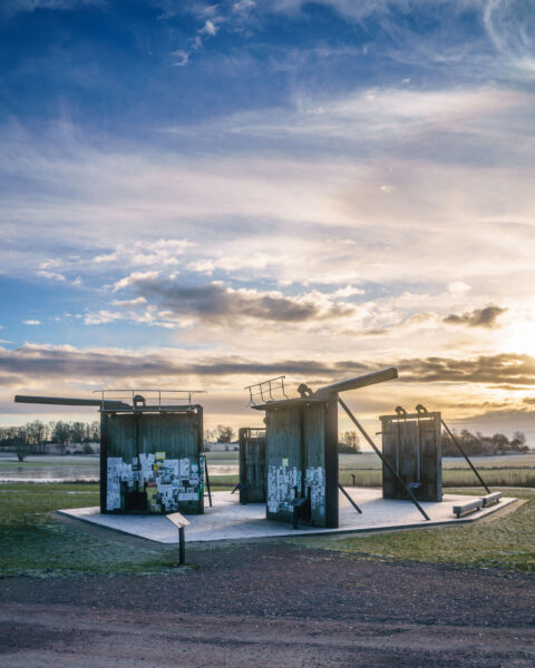 Slussportsmuseet vid Bergs slussar längs Göta kanal, tre skulpturala installationer i solnedgång med frostigt landskap i bakgrunden