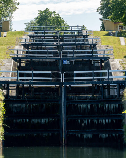 Borenshults slusstrappa vid Göta kanal i Motala, med flera slussportar i rad omgivna av gröna grässlänter en solig sommardag