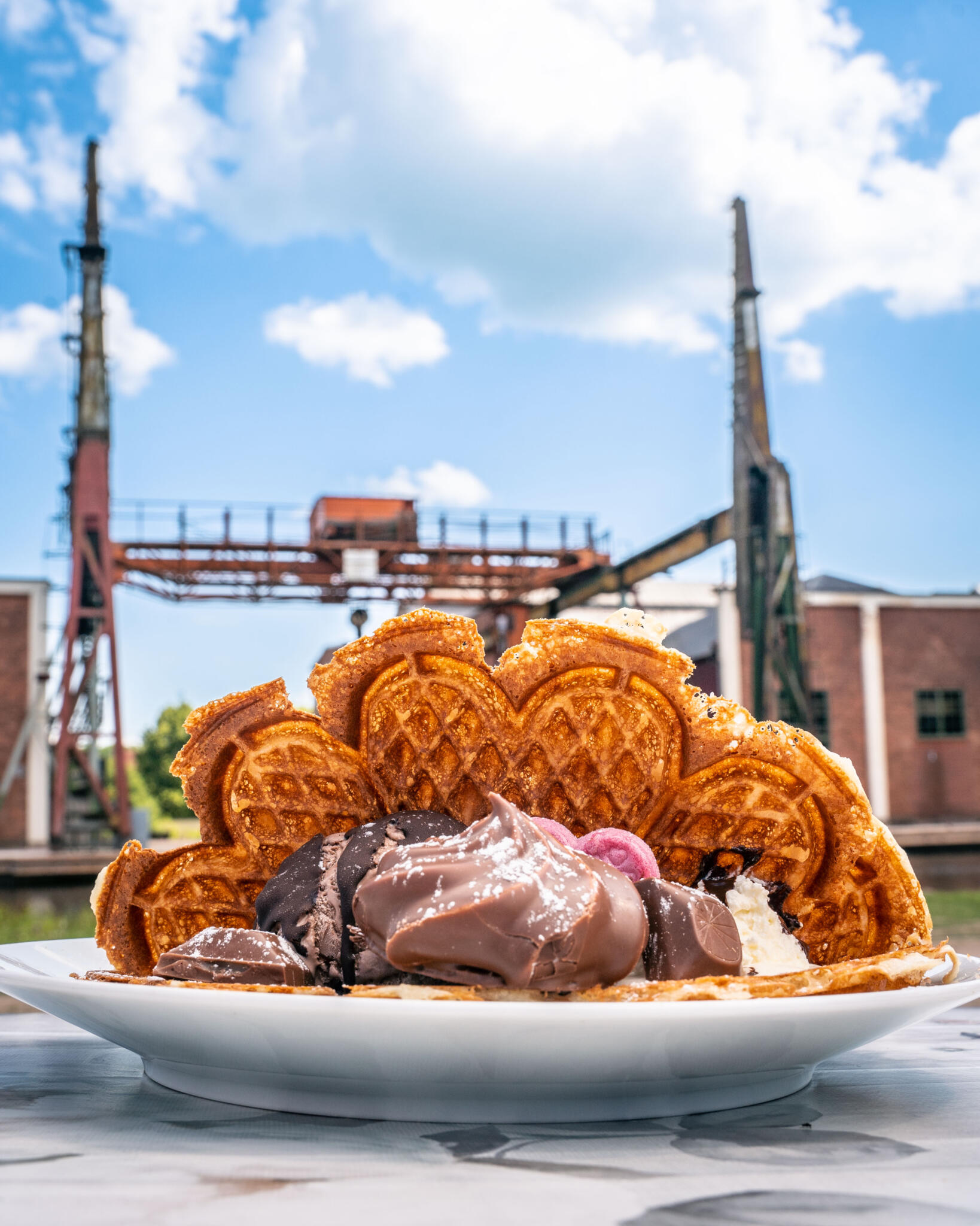 Våffla med choklad och glass serverad utomhus vid Mallboden i Motala med industriell hamnkran i bakgrunden