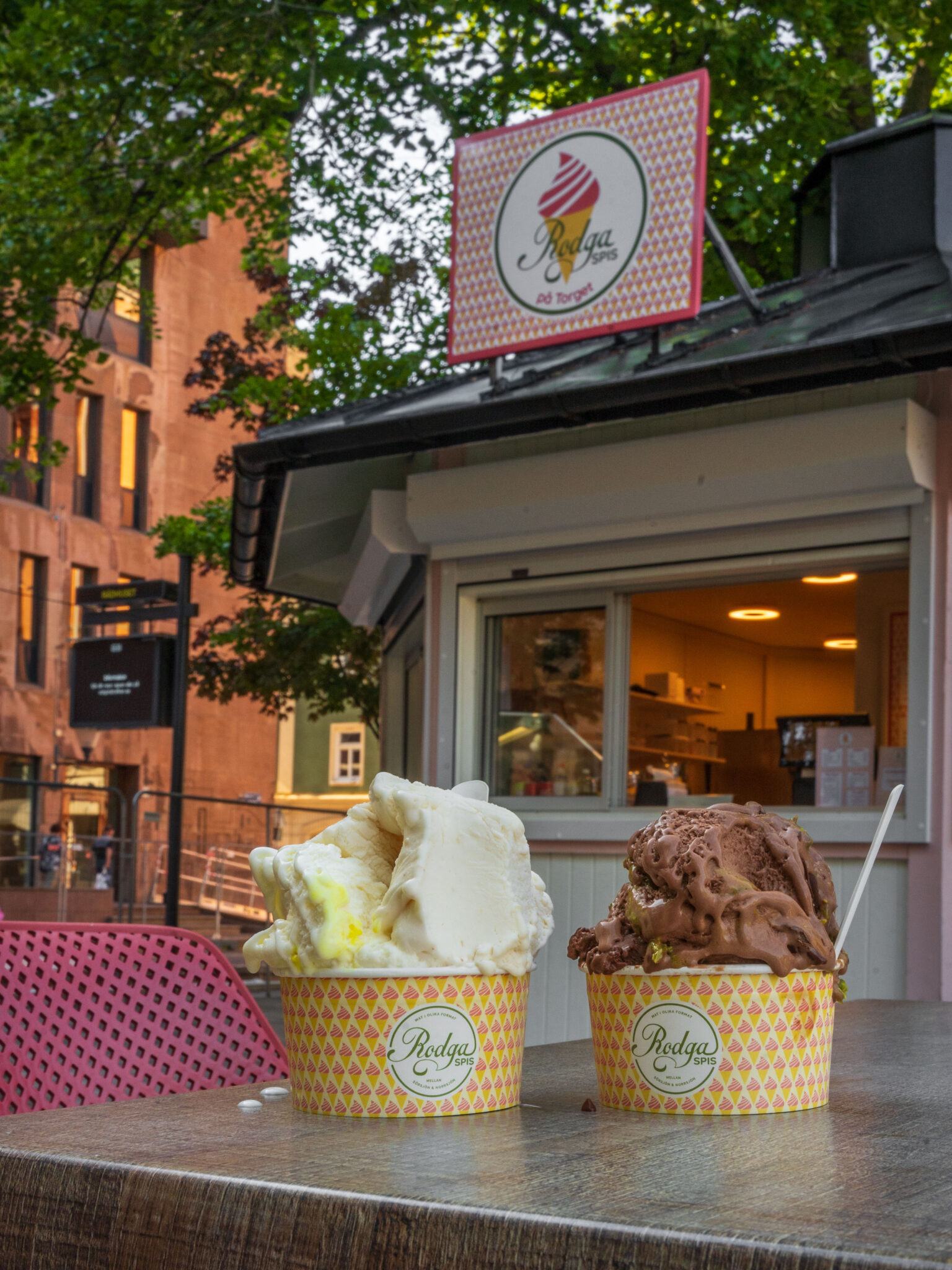 Två bägare med glass från Rodga Spis på Gamla Torget i Norrköping, en vanilj och en choklad, framför glasskiosken en sommardag.