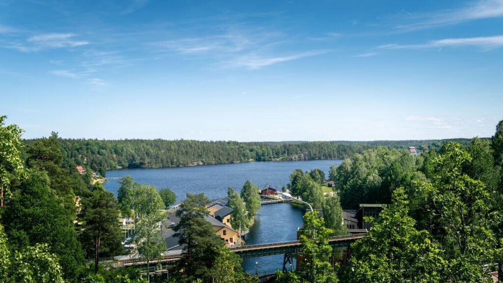 Utsikt över Håverud med akvedukten, Dalslands kanal och den omgivande sjön inramad av frodig grönska en sommardag