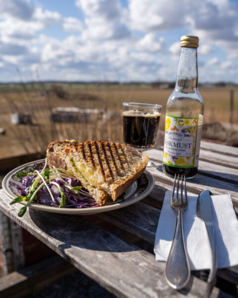 Grillad smörgås med sallad, kaffe och Brunneby påskmust på uteservering vid Boställets Vedugnsbageri med östgötaslätten i bakgrunden