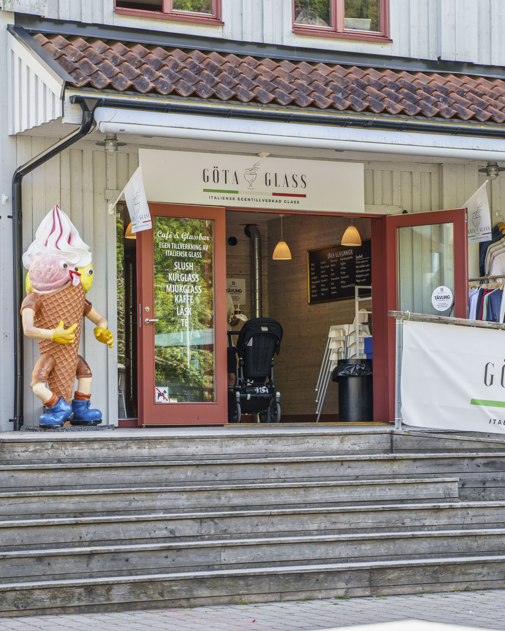 Entrén till Göta Glass i Söderköping med en stor glassfigur vid trappan och skylt som erbjuder italiensk egentillverkad glass, slush, mjukglass och kaffe.