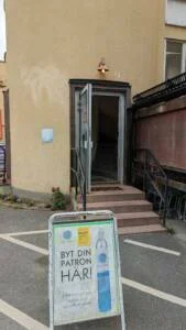 Entré till Björnes Magasin i Kisa med öppen dörr, trappa upp och gatupratare med Vikingsoda-reklam "Byt din patron här!"