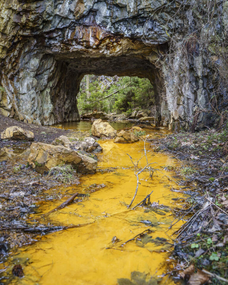 Orangegult svavelrikt vatten flödar genom gruvgång vid Sätragruvan i Finspångs kommun, Östergötland.