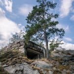 Militärbunker insprängd i berget vid Skans 453 i Dalsland, omgiven av tallar och karg klipphäll under blå himmel