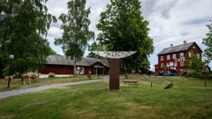 Dalslands konstmuseum med skulpturpark, röda träbyggnader och Café Bonaparte, omgivet av björkar och grönska i Upperud
