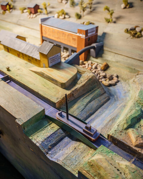 Detaljerad miniatyrmodell av en sluss med segelbåt och kanalbyggnader på Dalslands Kanalmuseum i Håverud