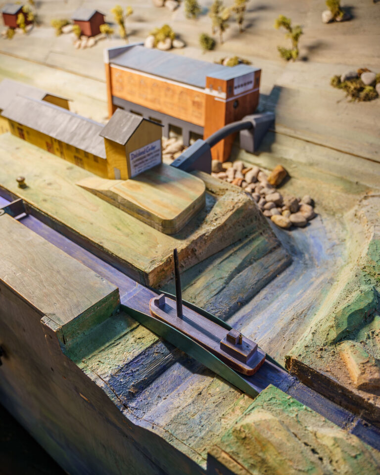 Detaljerad miniatyrmodell av en sluss med segelbåt och kanalbyggnader på Dalslands Kanalmuseum i Håverud