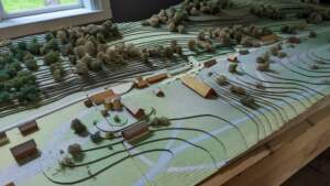 Detaljerad miniatyrmodell av Bäckefors gamla järnbruk med byggnader, åkermark och kullar, visad på hembygdsmuseet i Bäckefors, Dalsland