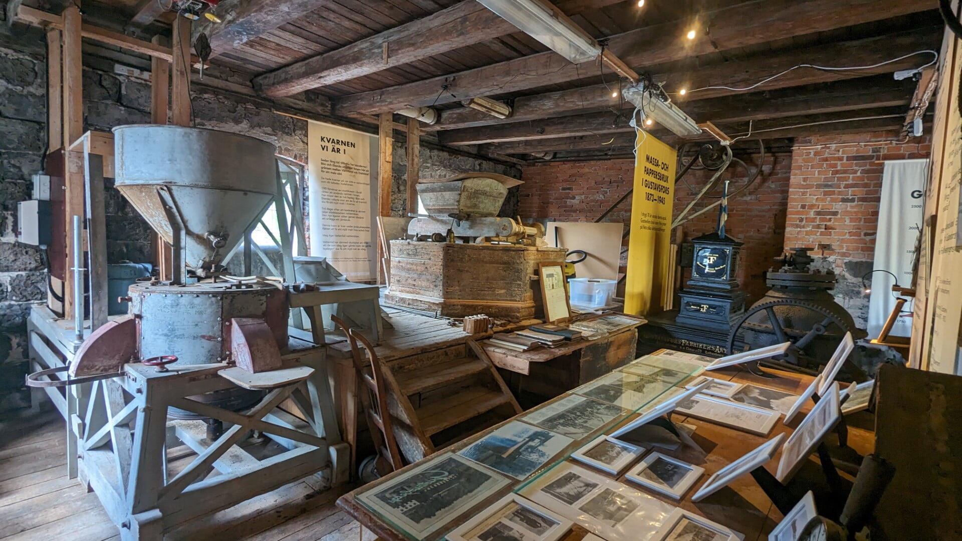 Interiör från Gustavsfors bruksmuseum med gammal kvarnutrustning, informationsskyltar och historiska fotografier i den gamla kvarnen.