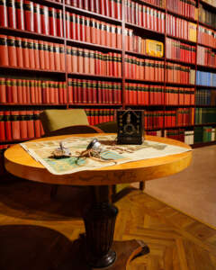 Biblioteksrum med antik kristallmottagare och hörlurar på ett runt träbord, framför bokhyllor med röda bokband, på Sveriges rundradiomuseum i Motala.