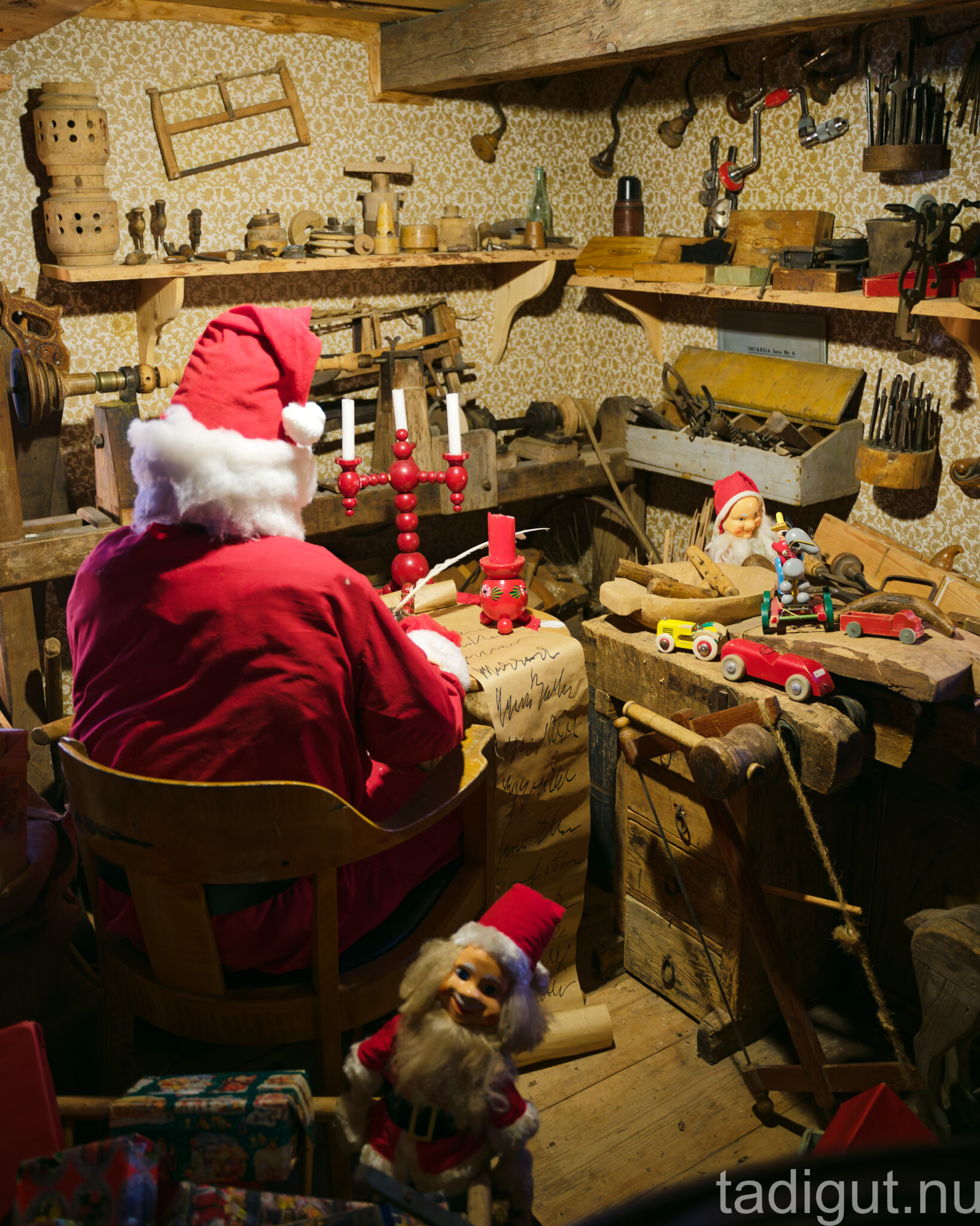 Tomte sitter vid en gammaldags verkstad med träleksaker, ljusstakar och tomtenissar på Kornettgårdens nostalgimuseum i Linköping