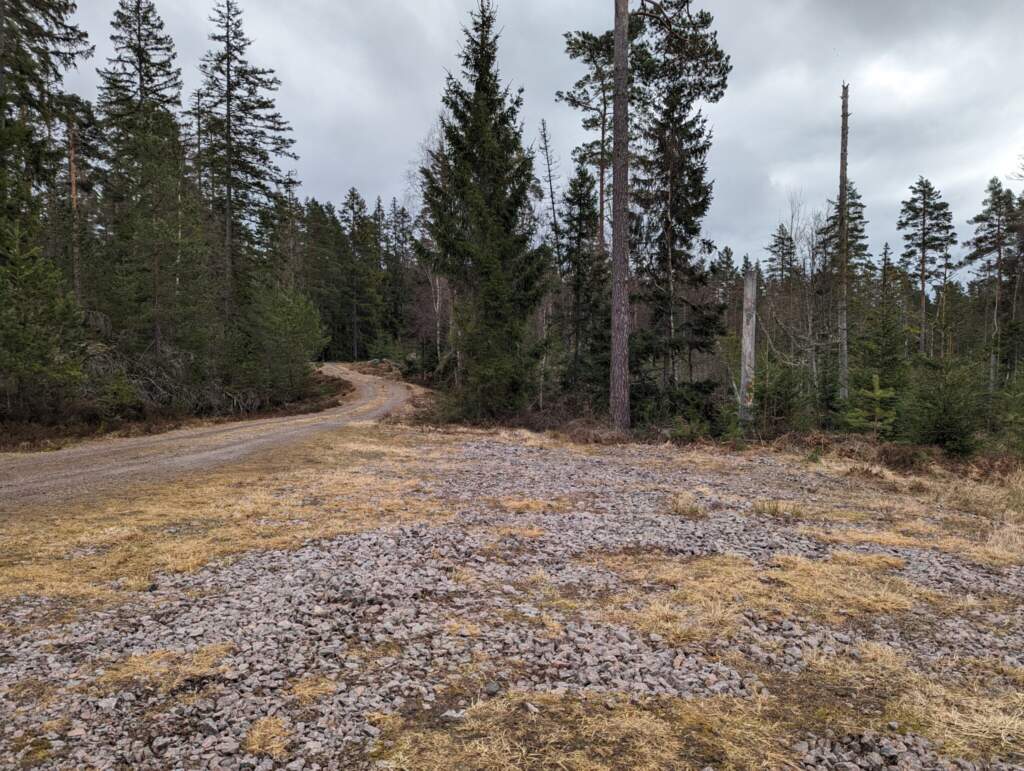 Grusad parkeringsplats vid Stora Boda naturreservat i Motala kommun, omgiven av barrskog med en skogsväg som leder in bland träden.