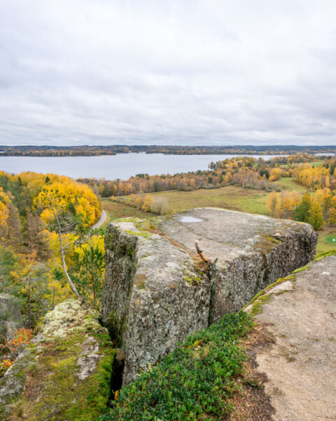 Utsikt från Klevberget i Kinda över höstfärgat landskap med sjön Ämmern, gröna ängar och gula lövträd en mulen dag.
