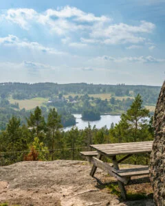 Utsiktsplats på Seloberget i Ydre med sittbänk på bergklippa och panoramavy över Sundsjöarna, skog och böljande landskap.