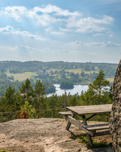 Utsiktsplats på Seloberget i Ydre med sittbänk på bergklippa och panoramavy över Sundsjöarna, skog och böljande landskap.
