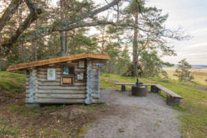 Timmrat vindskydd med informationsskyltar, sittbänk och grillplats vid Svensksundsleden i Svensksundsvikens naturreservat, Östergötland