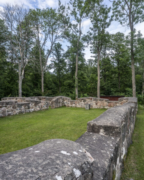 Kung Fredriks kyrkoruin vid Krokeks kloster med låga stenmurar, grönt gräs och lövträd i sommargrönska, Östergötland