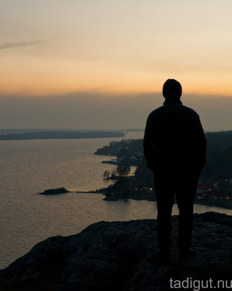 Siluett av en person på Kvarseboklint med utsikt över Bråviken i solnedgång, Östergötland