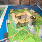 Miniatyrmodell av ett medeltida slott med torn, vallgrav och omgivande byggnader på museum i Söderköping