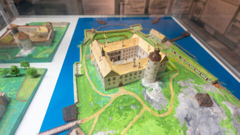 Miniatyrmodell av ett medeltida slott med torn, vallgrav och omgivande byggnader på museum i Söderköping