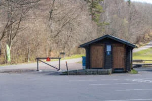 Toalettbyggnad i trä vid parkeringen på Omberg, Östergötland, omgiven av lövskog i tidig vår.