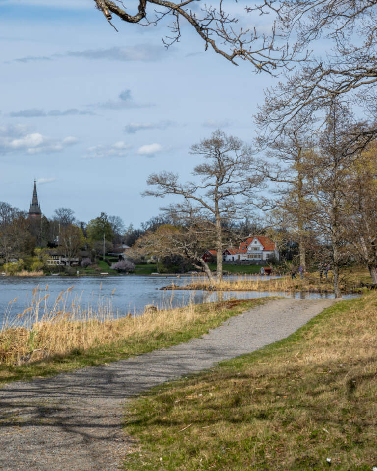 En gångväg slingar sig längs Bysjöns strand med Åtvidabergs kyrka i bakgrunden