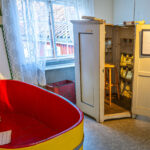 Röd och gul badbalja samt öppet vitmålat skåp med medicinsk utrustning på Lazarettsmuséet vid Medevi brunn i Östergötland