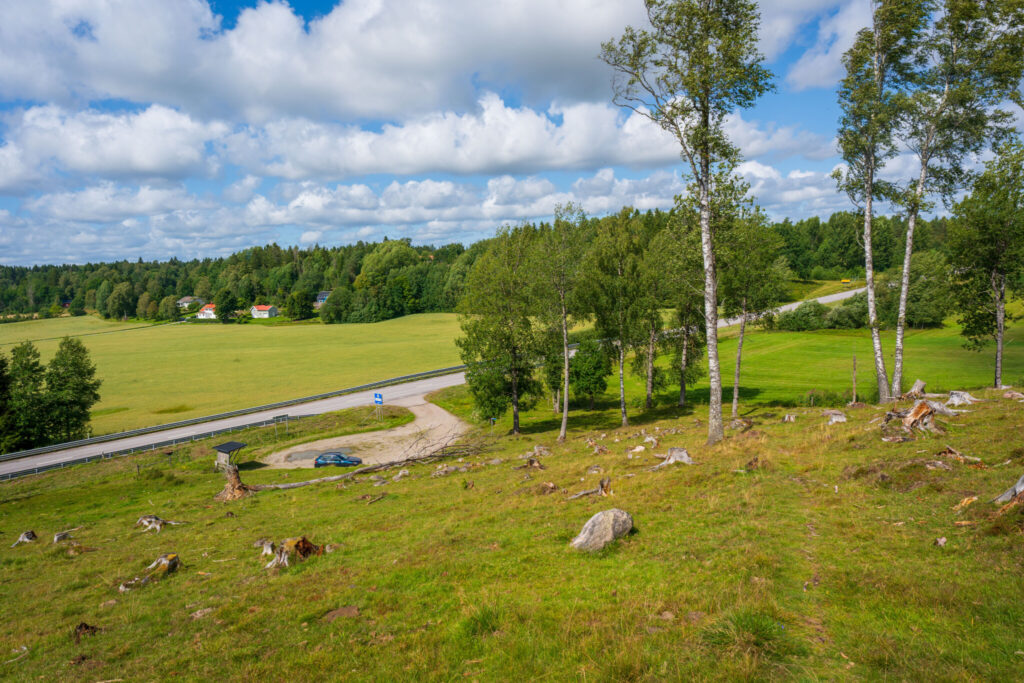 Utsikt från Ättekullshögen vid Håvesten över gröna betesmarker, björkar, landsväg och gårdar nära Ödeborg i Dalsland