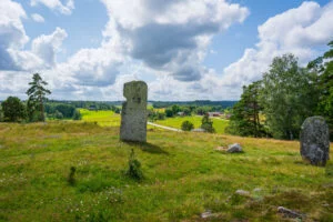 Resta stenar på Ättekullshögen vid Håvesten med utsikt över gröna betesmarker och röda stugor nära Ödeborg i Dalsland