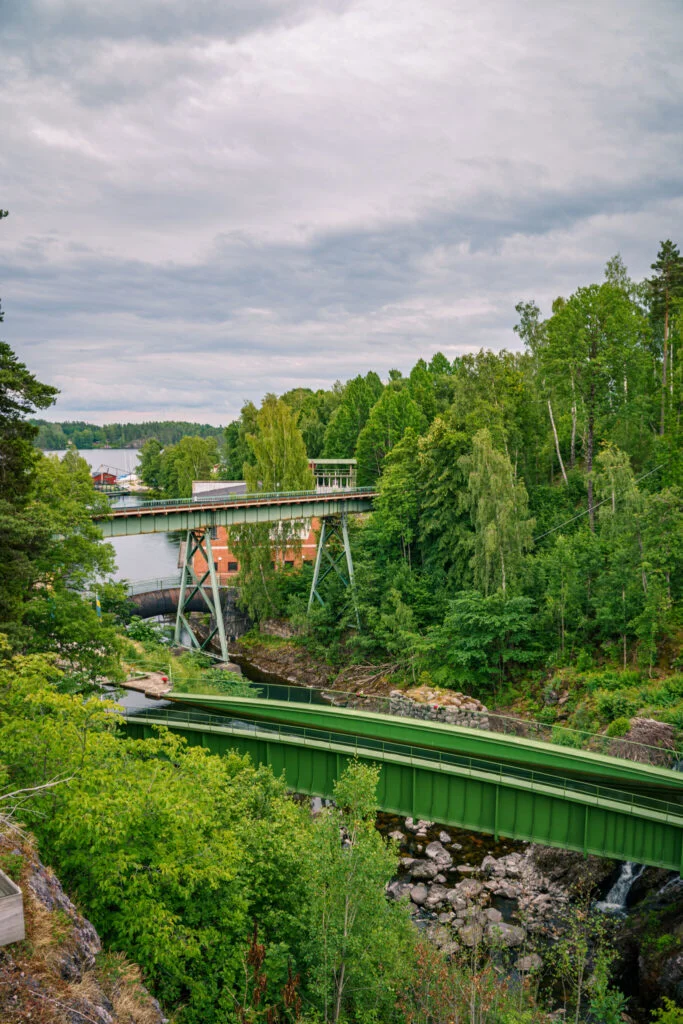 Gröna akvedukten i Håverud med bilbron ovanför, omgiven av frodig grönska och klippor längs Dalslands kanal.