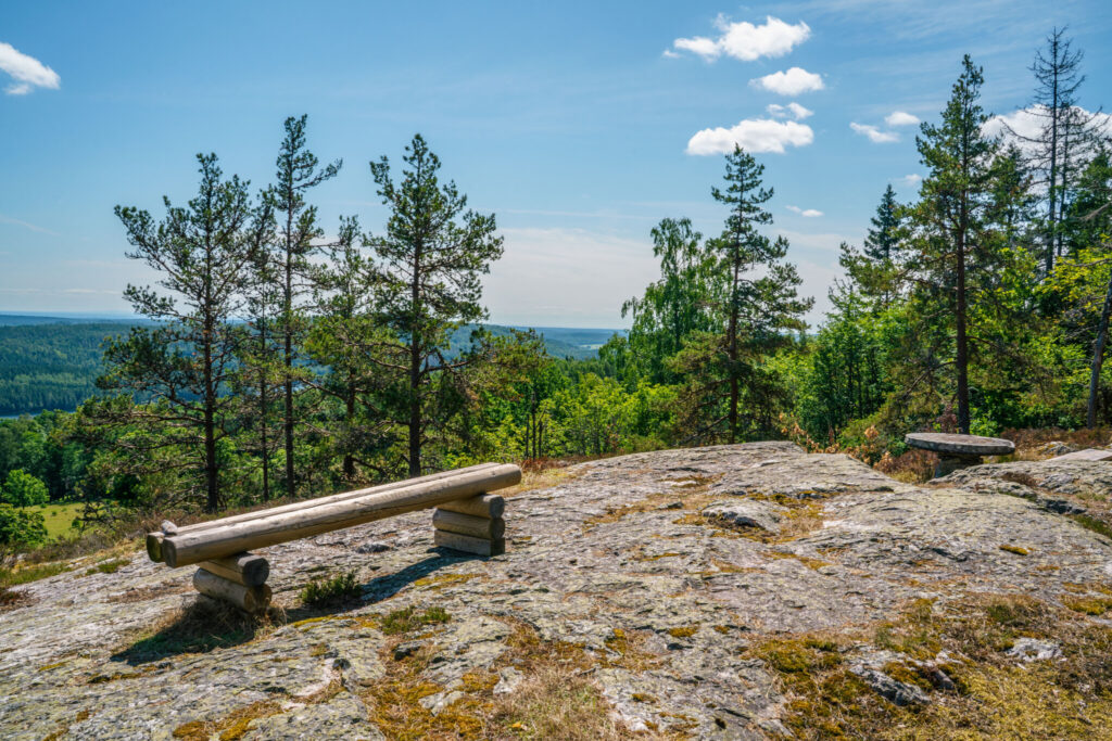 Utsiktsplats vid Linheden i Dalsland med träbänkar på berghäll, tallskog och vid utsikt över skogslandskapet mot Knarrbysjön