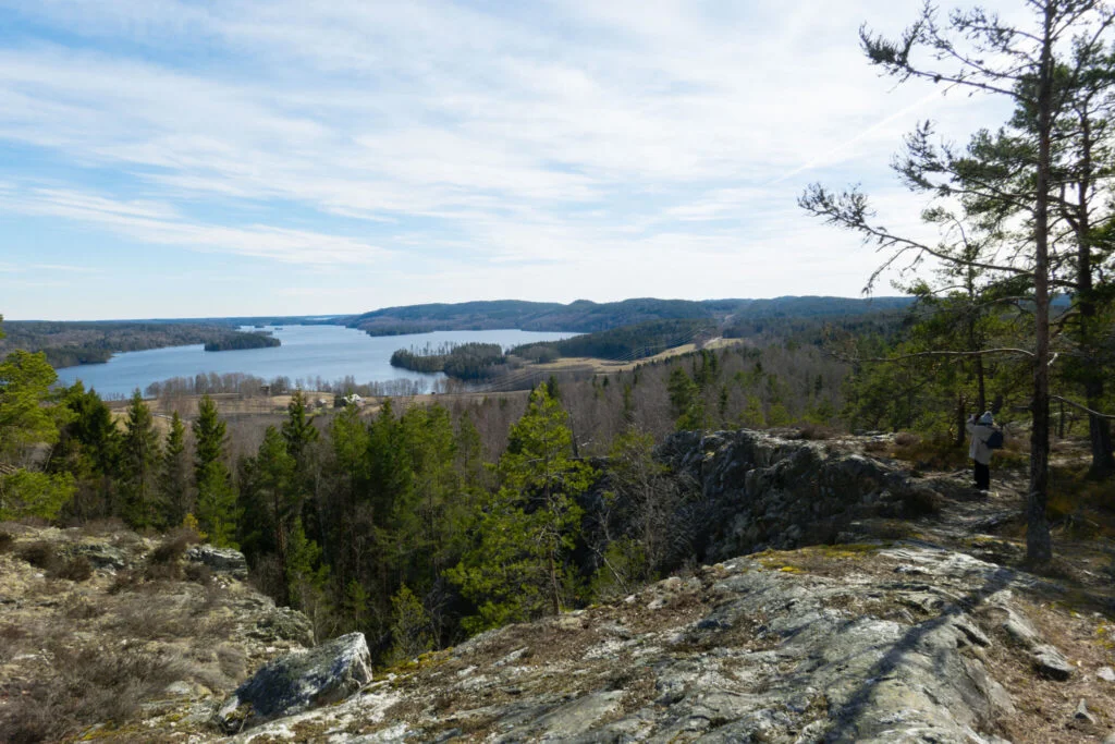 Utsikt från berget Bläsen över sjön Ärr och Dalslands skogslandskap, med klipphällar och tallar i förgrunden