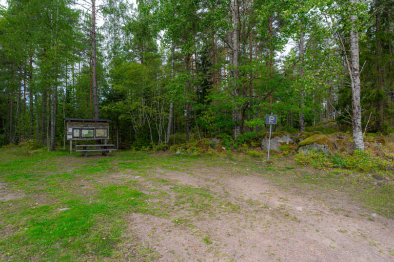 Parkering vid Lysings urskog naturreservat med informationstavla, parkeringsskylt och omgivande grön blandskog i Ödeshögs kommun.