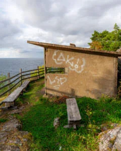 Vindskydd med graffiti och träbänkar vid klippkanten med utsikt över Vättern i Stora Lunds naturreservat, Ödeshög