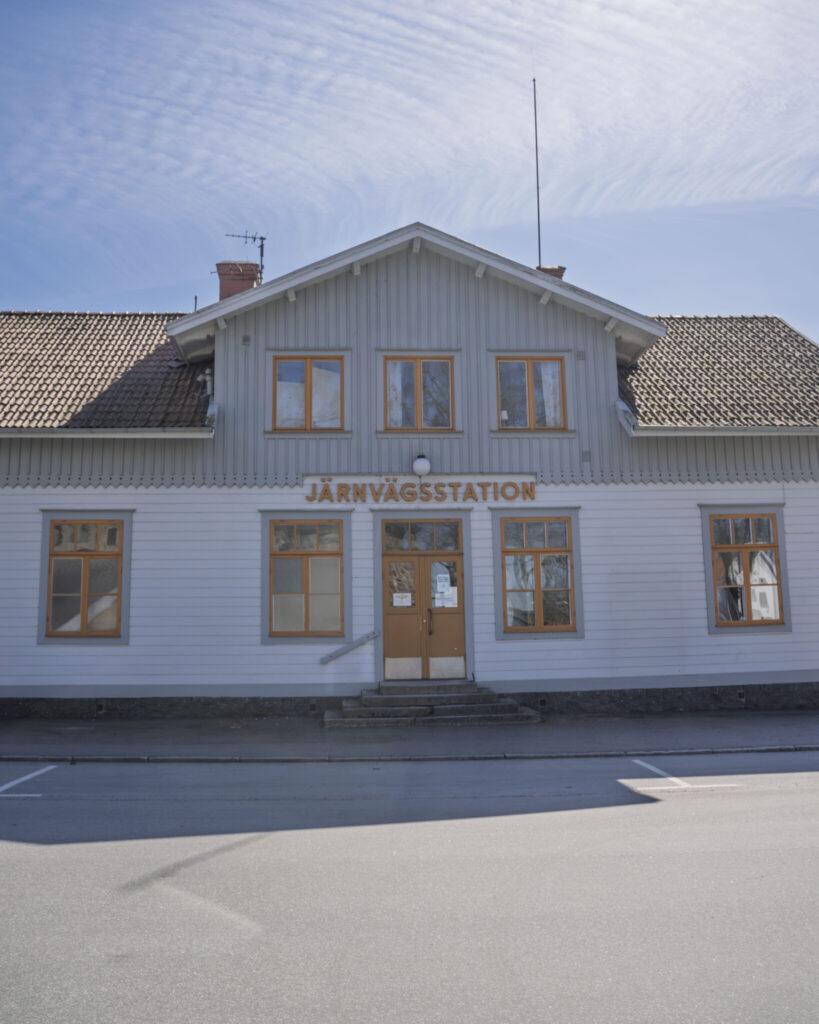 Vitmålat trähus med skylten "Järnvägsstation" ovanför entrén, Wadstena-Fogelsta Järnväg i Vadstena, Östergötland