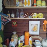 Hyllor med retroföremål i gult och orange – keramik, porslin, vaser och prydnader hos Maris Retro & Loppis nära Ulrika i Östergötland