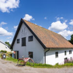 Vitputsad byggnad från 1775 med tegeltak som inrymmer Borensbergs hembygdsmuseum, med en röd cykel och museumsskylt vid fasaden.