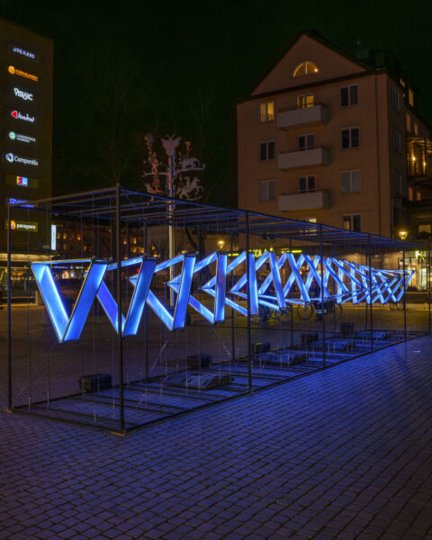 Blåupplyst ljusinstallation på Stora torget i Linköping under evenemanget Vinterljus, med stadsbebyggelse i bakgrunden en mörk kväll.